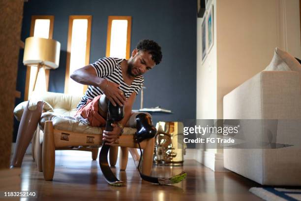 Young man putting prosthetic leg at home
