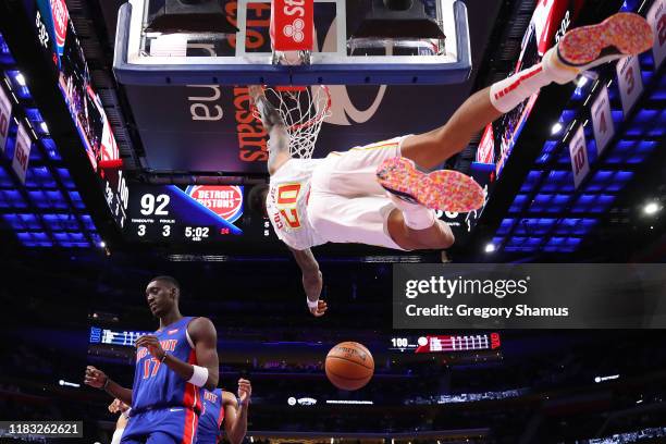 John Collins of the Atlanta Hawks dunks next to Tony Snell of the Detroit Pistons during the second half at Little Caesars Arena on October 24, 2019...