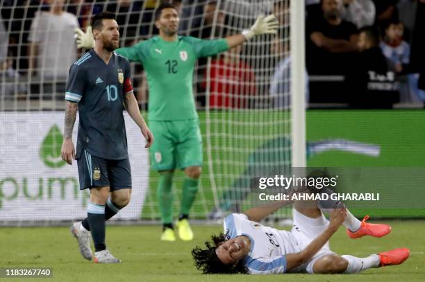 Uruguay's forward Edinson Cavani gestures on the ground near Argentina's forward Lionel Messi during the friendly football match between Argentina...