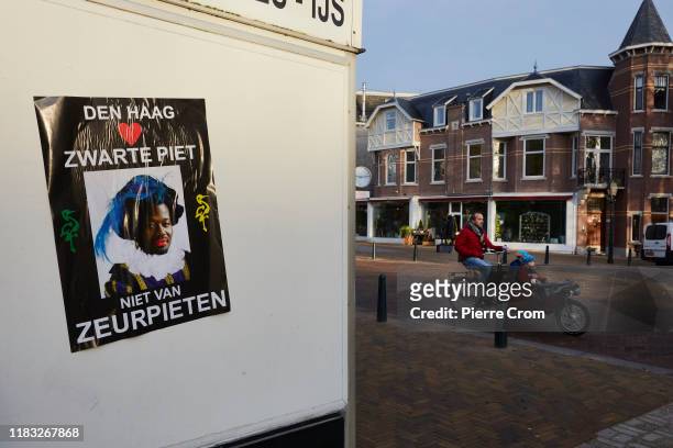Pro-blackface activists glued posters with Kick Out Zwarte Piet anti-blackface leader Jerry Afriyie seen dressed in Black Pete prior to the...
