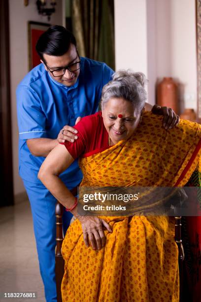 male nurse taking care of old woman suffering with knee pain - knee stock pictures, royalty-free photos & images