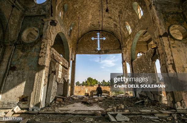 Member of the Khabour Guards Assyrian Syrian militia, affiliated with the Syrian Democratic Forces , sits in the ruins of the Assyrian Church of the...