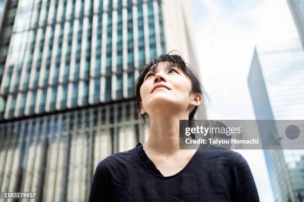 a woman looking up at a building in tokyo - growth mindset stock pictures, royalty-free photos & images