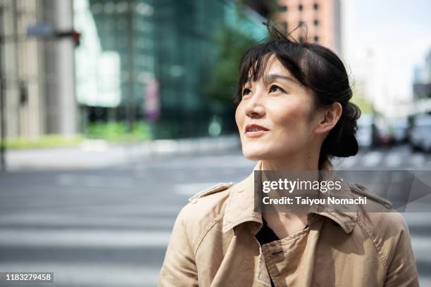 portrait of a japanese woman photographed in tokyo - japanese bussiness woman looking up stock-fotos und bilder