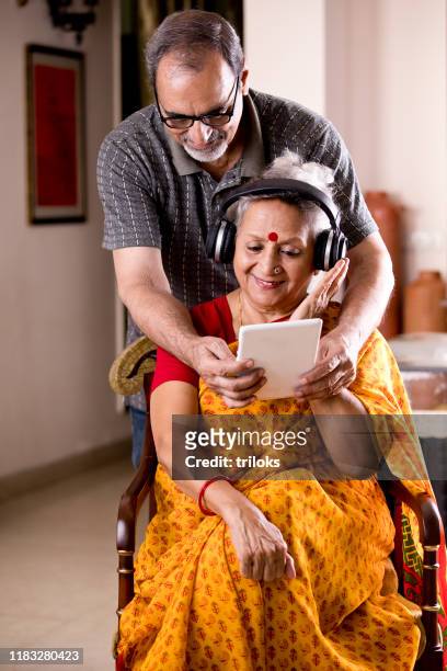 senior couple having fun watching media content on digital tablet at home - indian elderly couple stock pictures, royalty-free photos & images