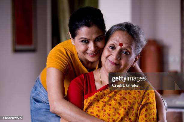 frau umarmt seniorin von hinten - indian mother daughter stock-fotos und bilder