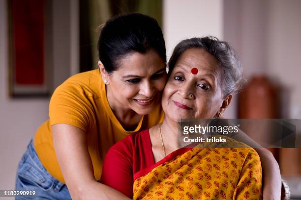 woman embracing senior mother from behind - sogra imagens e fotografias de stock