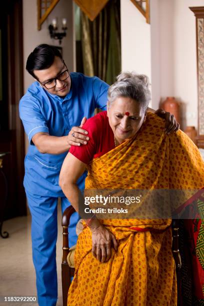 male nurse taking care of old woman suffering with knee pain - bone stock pictures, royalty-free photos & images