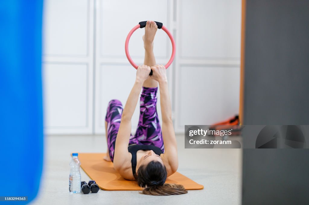 Lying on back and stretching raised leg with pilates ring