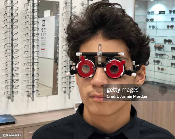 latin teenage boy examining eyes - phoroptor stock pictures, royalty-free photos & images