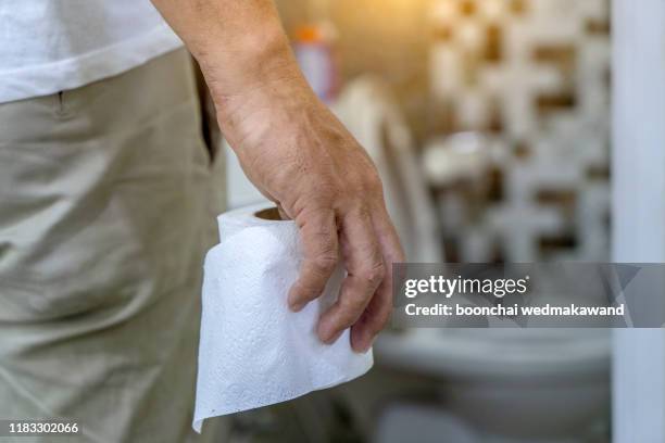 man holding toilet tissue roll in bathroom looking at loo - bidet stock-fotos und bilder