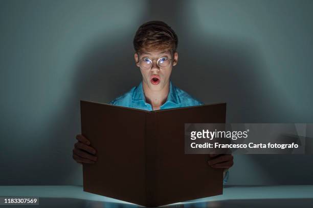 teen reads a book in the night - glowing book stock pictures, royalty-free photos & images