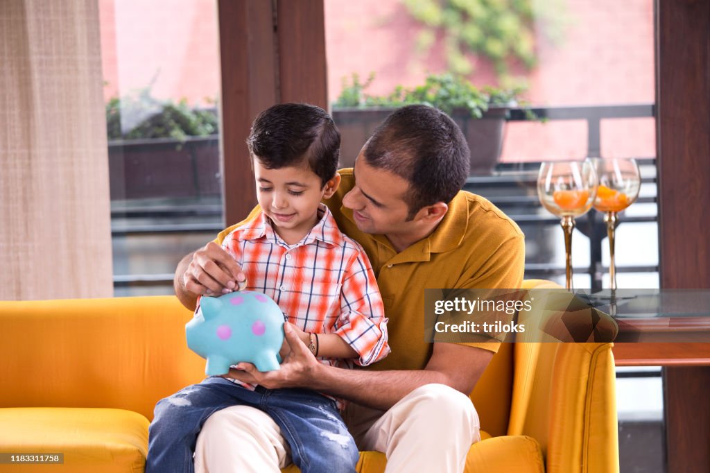 Father and son with piggy bank at home