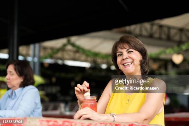 retrato de mujer mayor bebiendo en un jugo en un restaurante - mature latin women fotografías e imágenes de stock