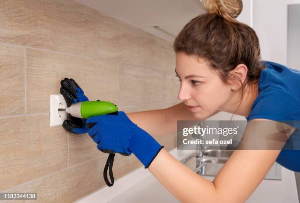 toma de corriente eléctrica reparación de mujeres en la cocina - conceptos de bricolaje - toma eléctrica fotografías e imágenes de stock