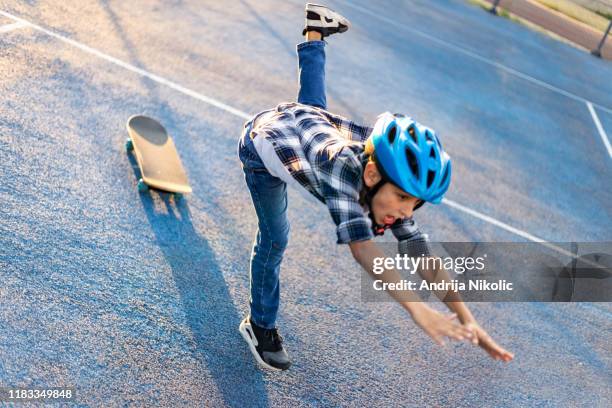 schuljunge mit einem helm fällt von seinem skateboard - skateboard fall stock-fotos und bilder