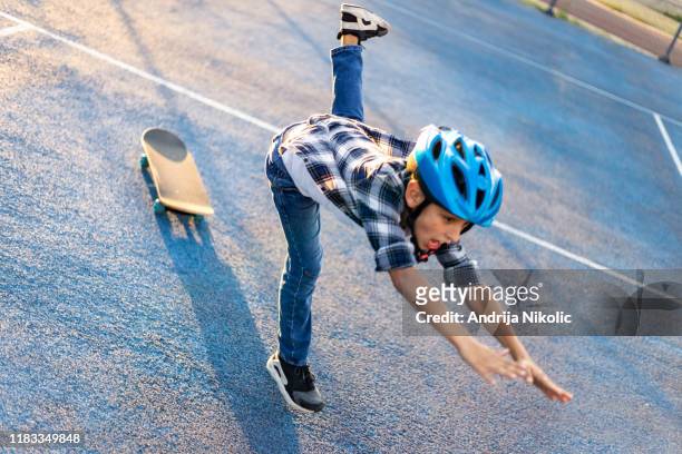 schoolboy with a helmet falling from his skateboard - slip stock pictures, royalty-free photos & images