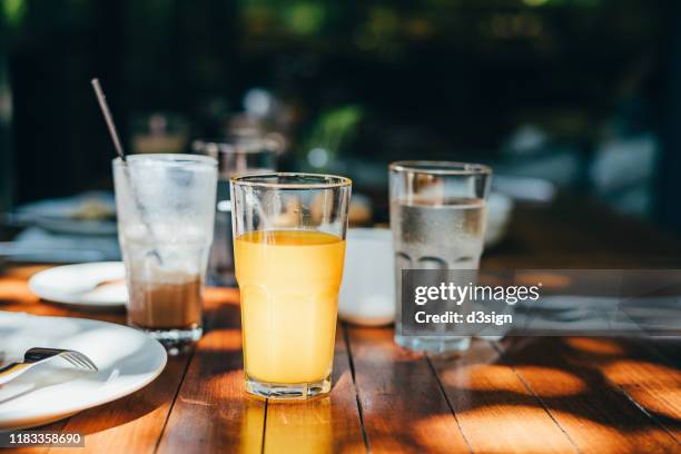 a glass of water, orange juice and coffee served on table in an outdoor restaurant against beautiful sunlight - 3 d glasses foto e immagini stock