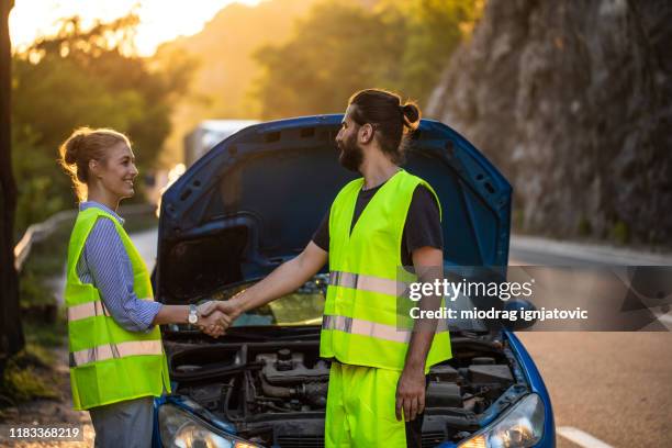 roadside assistance worker and woman shaking hands after fixing car breakdown - vehicle breakdown imagens e fotografias de stock