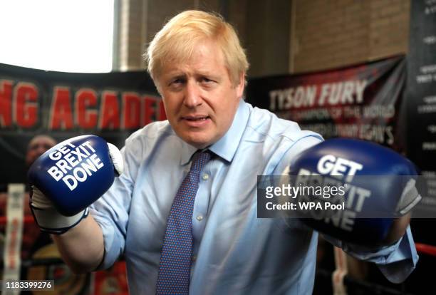Britain's Prime Minister Boris Johnson poses for a photo wearing boxing gloves emblazoned with "Get Brexit Done" during a stop in his General...