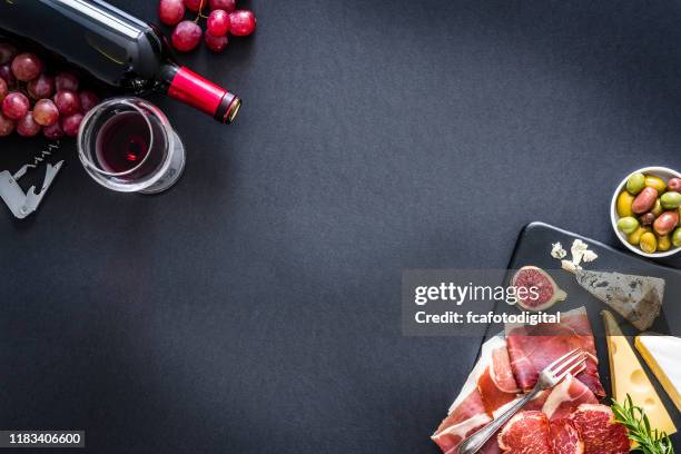 appetizer frame: red wine, cured ham and cheese on on black background - food table edge stock pictures, royalty-free photos & images