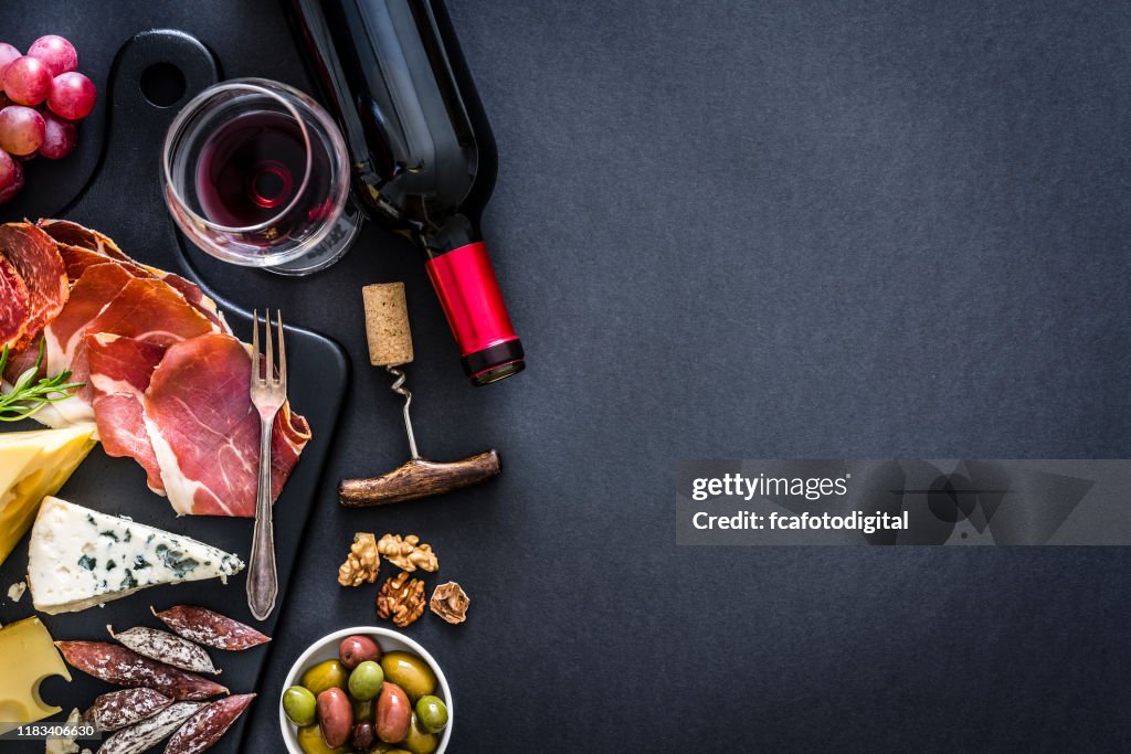 Appetizer frame: red wine, Iberico ham and cheese on rustic table