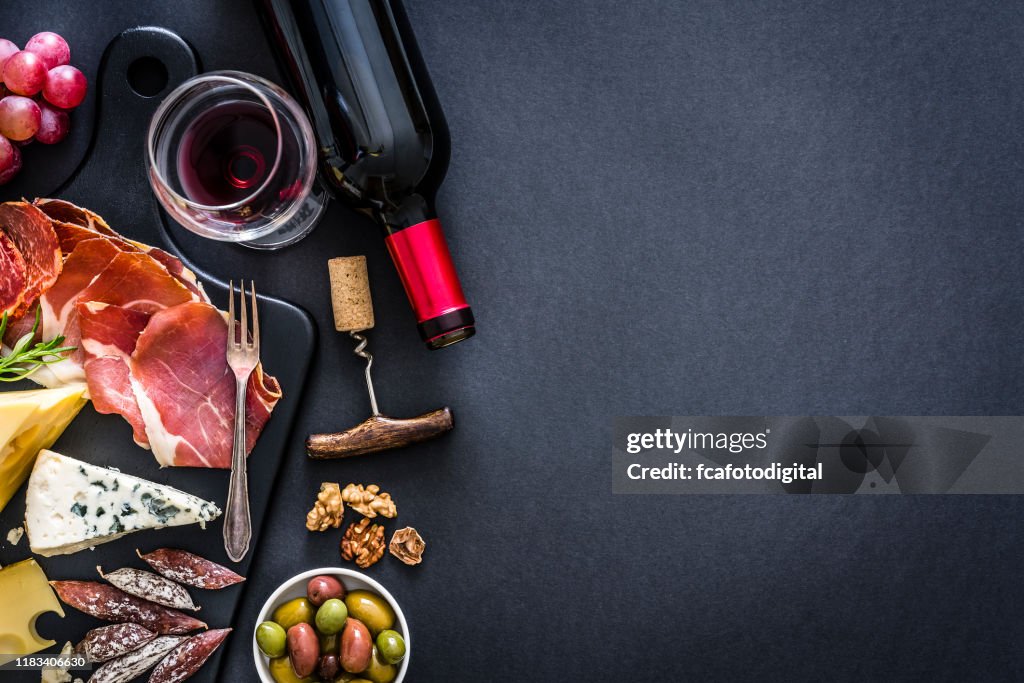 Quadro do aperitivo: vinho tinto, presunto de Iberico e queijo na tabela rústica