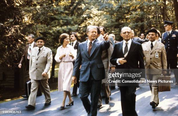 Accompanied by a large group of others, US President Jimmy Carter and Israeli Prime Minister Menachem Begin walk together during the Egyptian-Israeli...