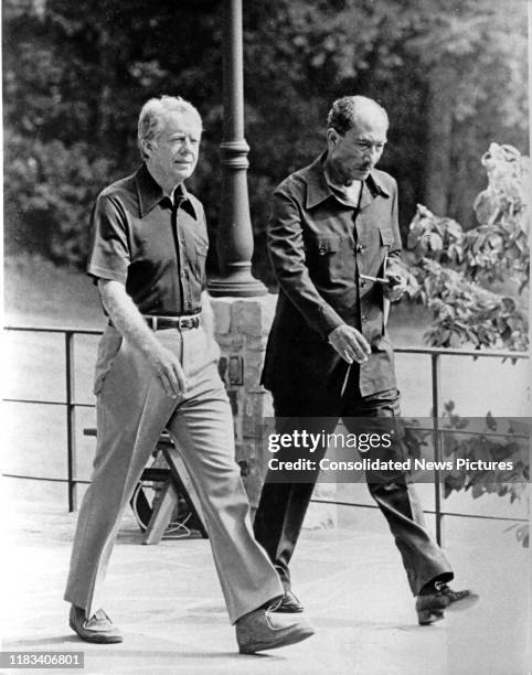 President Jimmy Carter and Egyptian President Anwar Al Sadat walk together during the Egyptian-Israeli peace negotiations, behind Aspen Lodge at Camp...