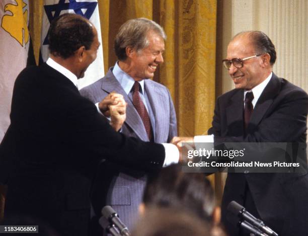 View of, from left, Egyptian President Anwar Al Sadat , US President Jimmy Carter , and Israeli Prime Minister Menachem Begin share a 3-way handshake...