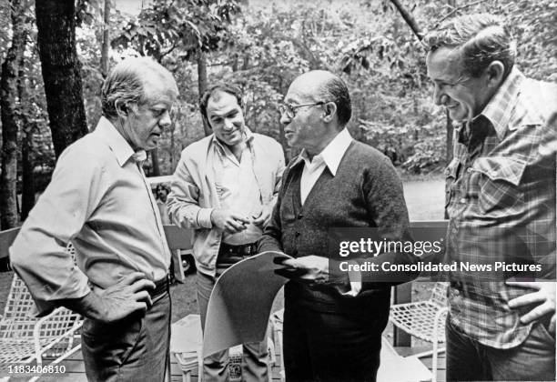 Along with a pair of unidentified aides, US President Jimmy Carter and Israeli Prime Minister Menachem Begin look at photographs during the...