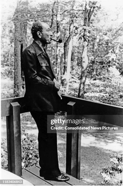 Egyptian President Anwar Al Sadat smokes his pipe during the Egyptian-Israeli peace negotiations at Camp David, outside of Dogwood Cottage at Camp...