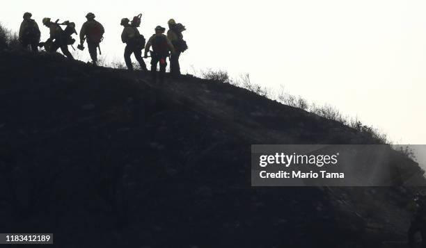 Firefighters make their way up a hillside charred by the Tick Fire on October 25, 2019 in Canyon Country, California. The fire has blackened 4,300...