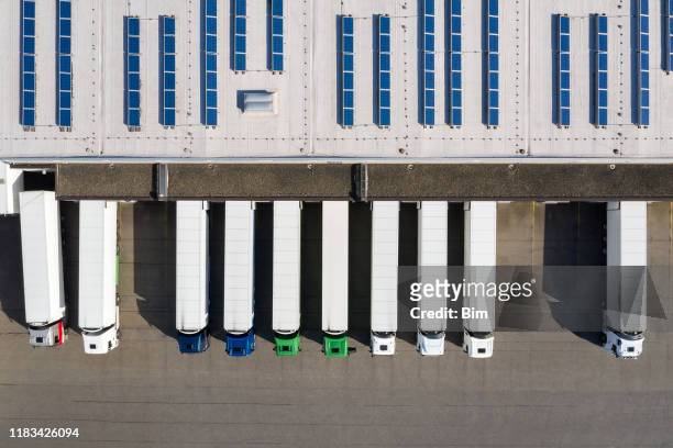 aerial view of semi-trucks loading at logistic center, distribution warehouse - truck stock pictures, royalty-free photos & images