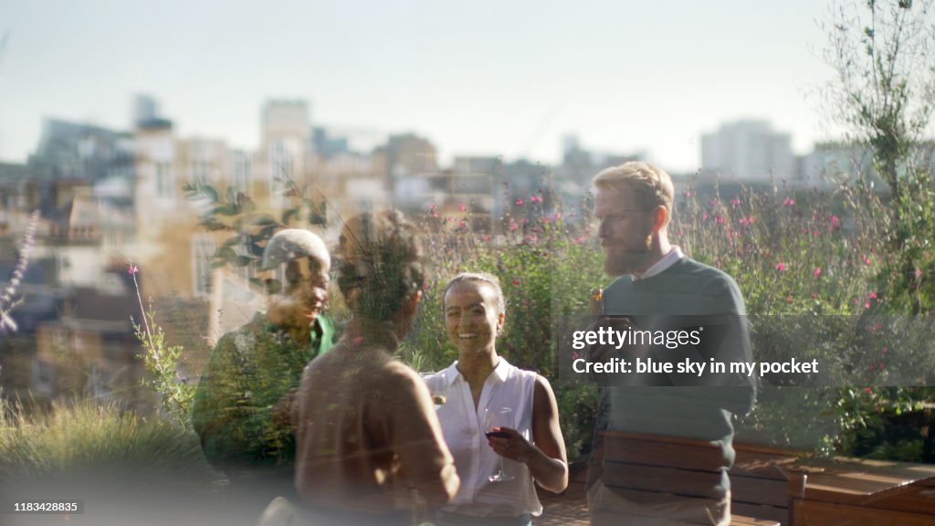 A small group of coworkers socialising together on a terrace in summer