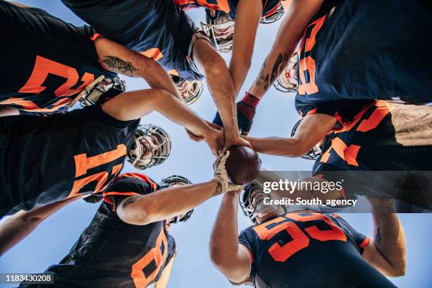 jugadores de fútbol americanos huddling - abrazo de grupo fotografías e imágenes de stock