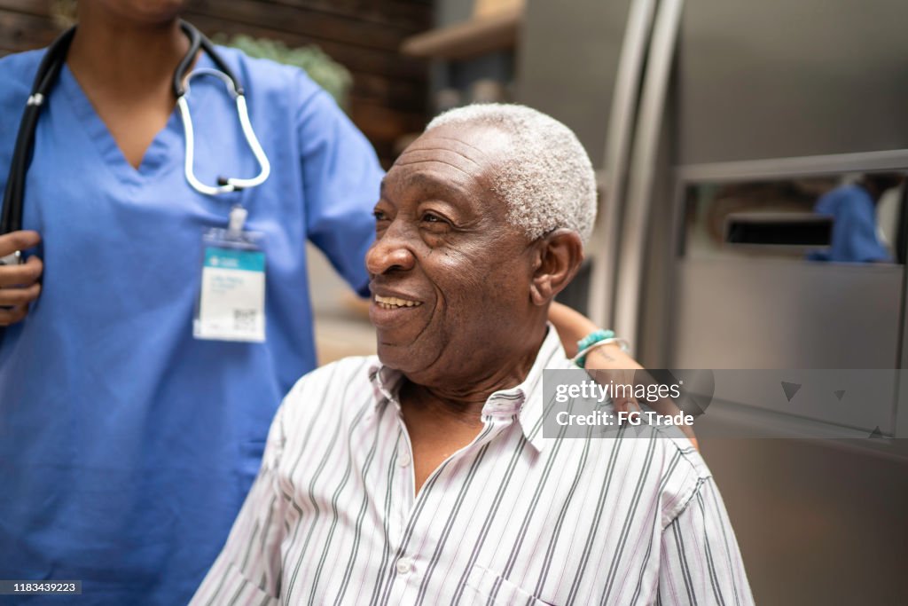 Senior man sitting, nurse behind him