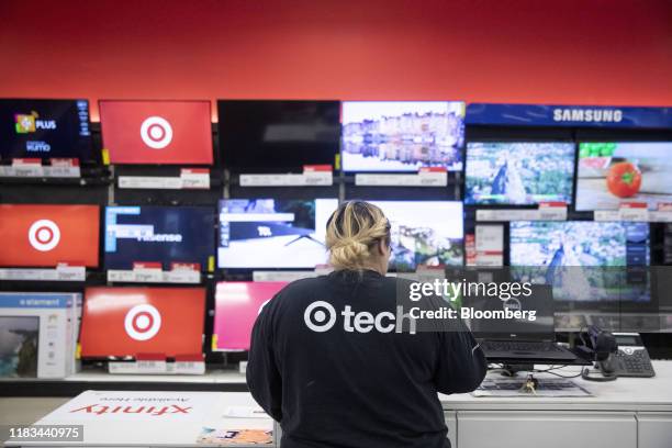 An employee stands at a register in front of a display of flatscreen televisions at a Target Corp. Store in Chicago, Illinois, U.S., on Saturday,...