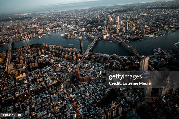 vista aérea de la hora dorada del puente de brooklyn, el puente de manhattan y el puente williamsburg que llega de brooklyn a manhattan, nueva york, tomado desde un helicóptero sobre la isla del bajo manhattan - brooklyn bridge fotografías e imágenes de stock
