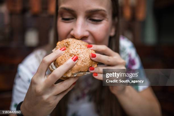 vrouw eten hamburger - woman eating burger stockfoto's en -beelden