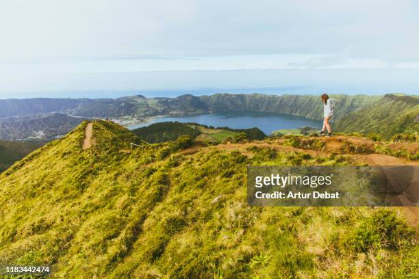 woman walking on the top of mountain with volcano crater view in the azores. - azores people stock pictures, royalty-free photos & images