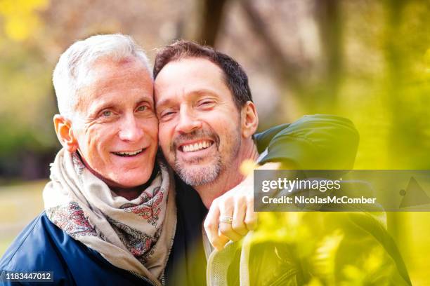 pareja de hombres gay de edad mayor amorosoretrato en un parque a finales de octubre - gay seniors fotografías e imágenes de stock