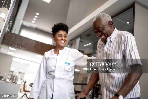 cuidador que ayuda a un hombre mayor con walker - black female nurse fotografías e imágenes de stock