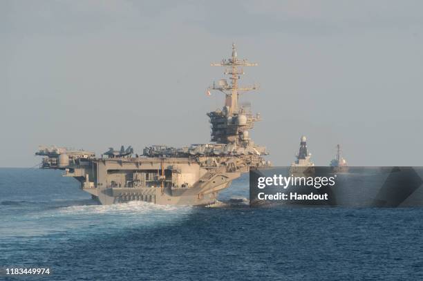 In this handout photo provided by the US Navy, The aircraft carrier USS Abraham Lincoln , left, the Royal Navy air defense destroyer HMS Defender and...