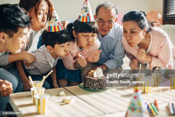 compleanno della bambina - parents children blow candles asians foto e immagini stock