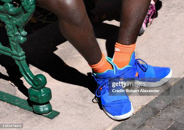 Young African-American man wearing Nike Paul George basketball shoes sits on a park bench in Santa Fe, New Mexico.