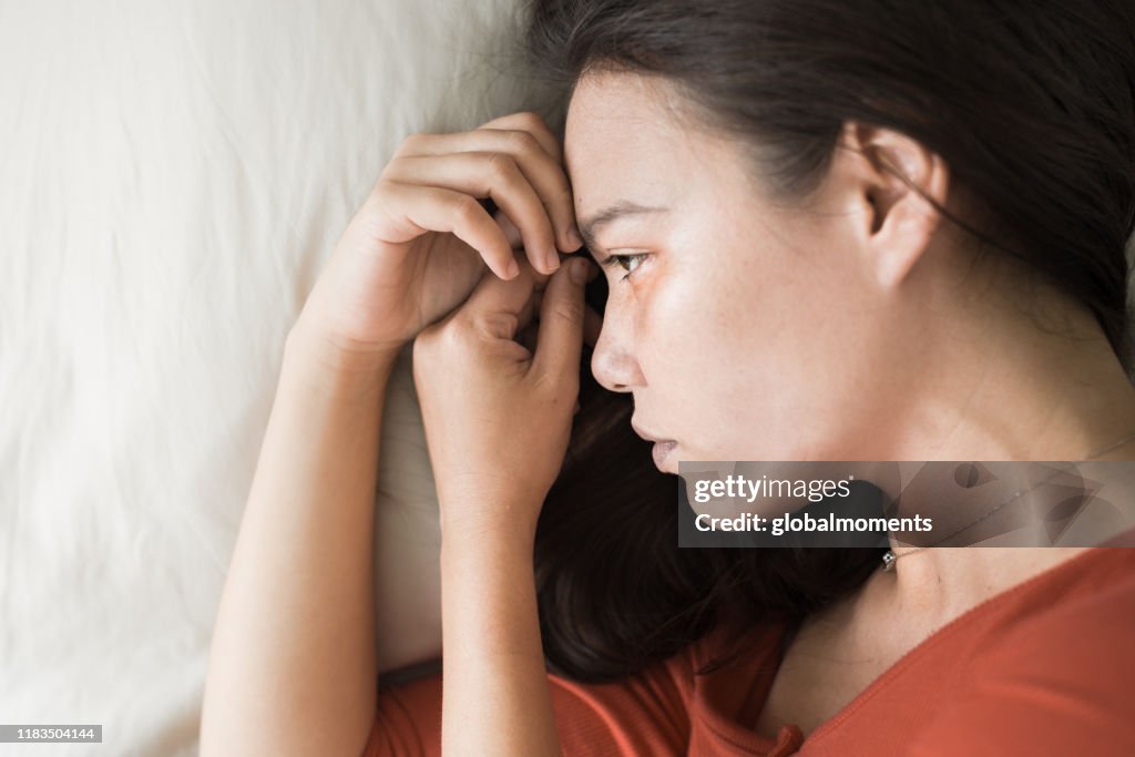 A sad depressed woman lying in bed.