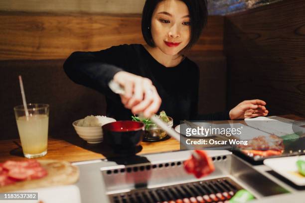 young woman putting raw beef on grill - たれ ストックフォトと画像