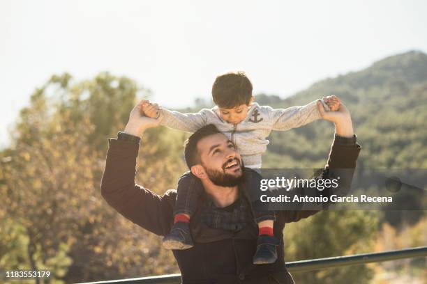 father playing outdoors with son carrying - happy fathers day fotografías e imágenes de stock