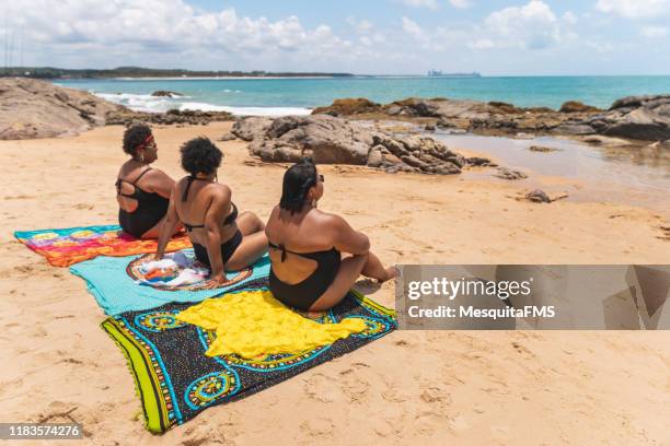 rear view of women sitting in beach sarong - black women in bathing suit stock pictures, royalty-free photos & images